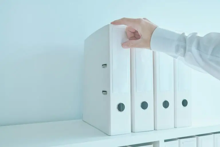 Accountant bookkeeper reaching for document ring binder from the office shelf